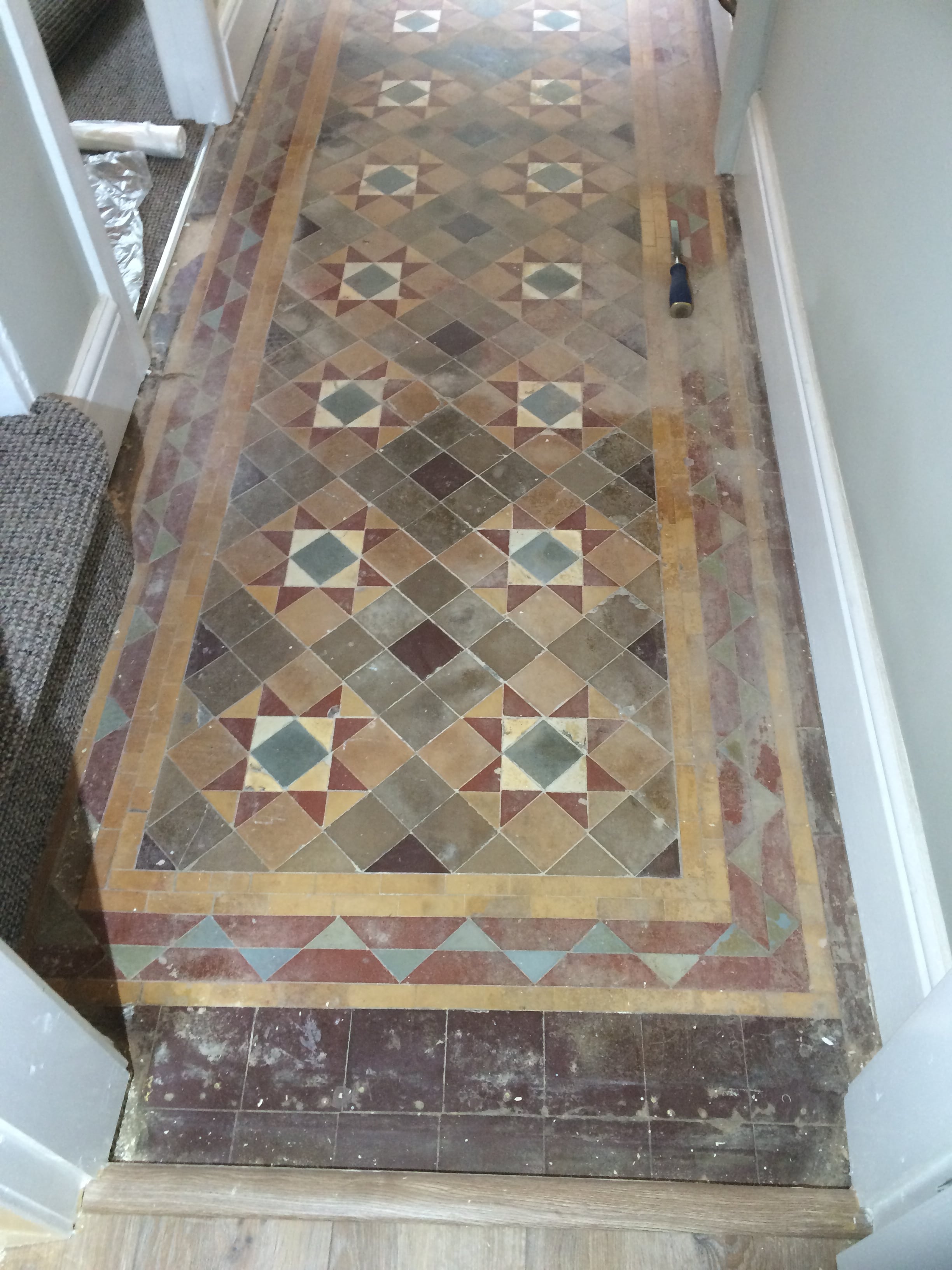 <a href='http://www.tiledoctor.co.uk/shop/category.aspx/victorian-tile-cleaning/11/?affillink=MWP1231' target='_blank'> Victorian Tiles </a> Before Renovation Burnley” width=”500″ height=”750″ title=”Victorian Tiles Before Renovation Burnley” /></p>
<p>On our initial visit I conducted a survey of the floor to check its condition and work out the most suitable products and methods to employ to restore it.  One of the main concerns we have with these old floors is damp as damp-proof membranes were not invented until relatively recently.  I have a damp meter to check for this and it did indicate high moisture levels which isn’t really an issue for cleaning the floor but would restrict our choice of sealer to those which are fully breathable and allow moisture to rise-up through the tile.   We agreed a price and schedule with the customer and within two weeks we were able to start the work.</p>
<h2>Cleaning an Original Victorian Tiled Hallway Floor</h2>
<p>The floor was in quite a state, made worse I suspect by recent restoration work by other contractors who unfortunately didn’t take as much care with the floor as the could have done.   </p>
<p>After protecting the skirting boards and carpets with film work got underway starting by applying a strong dilution of <a href=